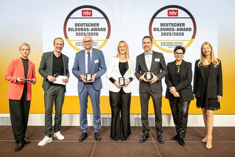 Gruppenfoto von sieben Personen auf einer Bühne während der Verleihung des Deutschen Bildungs-Awards 2025/2026. Die Personen stehen vor zwei großen projizierten Award-Logos von ntv und dem Deutschen Institut für Service-Qualität. Mehrere ausgezeichnete Vertreterinnen und Vertreter halten ihre Trophäen sichtbar in den Händen. Die Szene ist professionell ausgeleuchtet, und alle Personen blicken lächelnd in die Kamera. Das Bild entstand im Rahmen der Preisverleihung, bei der die International School of Management als Gesamtsiegerin in der Kategorie ‚Private Business Schools‘ ausgezeichnet wurde.