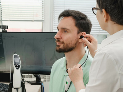 Das Bild zeigt eine medizinische Fachkraft, die das Ohr eines Patienten untersucht. Eine gängige Gesundheitsuntersuchung.