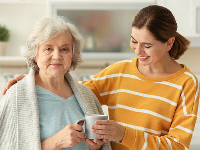 Das Bild zeigt zwei Personen, eine ältere und eine junge Frau, während sie eine Tasse genießen.
