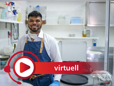 Ein lächelnder Mann in einer Küchenumgebung trägt eine blaue Schürze über einem weißen Hemd und Handschuhe. Er steht vor einem Arbeitstisch, auf dem eine Pfanne und andere Küchenutensilien zu sehen sind. Im Vordergrund ist ein rotes Symbol mit einem Play-Button und dem Wort 'virtuell' eingeblendet. Im Hintergrund sind Regale mit Küchenzubehör wie Reinigungsmitteln und Behältern zu erkennen.