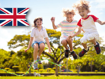 Drei Personen springen Seil unter sonnigem Himmel, britische Flagge im Hintergrund.