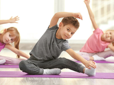 Das Bild zeigt Kinder, die Yoga praktizieren. Es betont die Bedeutung von körperlicher Aktivität und Wohlbefinden bereits im jungen Alter.