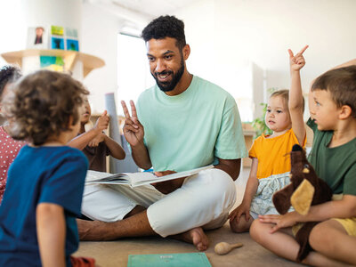 In diesem Bild liest ein Erwachsener Kindern vor, die aufmerksam zuhören und reagieren.
