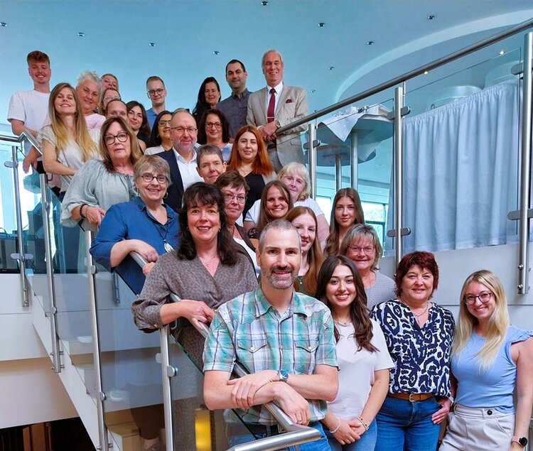 Teilnehmerinnen und Teilnehmer der Tagung des Bereichs Finanzen posieren gemeinsam auf einer Treppe hintereinander stehend für ein Gruppenbild.