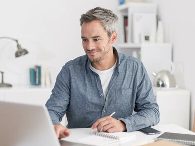 Auf dem Bild arbeitet eine Person an einem Laptop in einem hellen Raum.