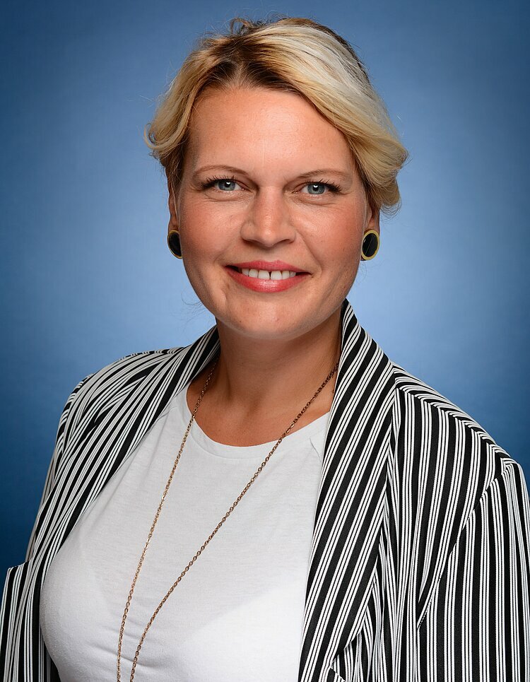 Portätfoto von Hannah-Mandy Hamperl-Freimund mit blauem Hintergrund