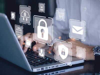 Eine Person arbeitet an einem Laptop, während verschiedene Symbole für Sicherheit und Technologie über der Tastatur schweben. Diese Symbole umfassen ein Vorhängeschloss, eine Cloud mit einem Pfeil, ein Benutzersymbol, ein Schild, einen Globus, einen Einkaufswagen, einen Briefumschlag und einen Fingerabdruck. Die Person trägt eine Armbanduhr und ein weißes Hemd.